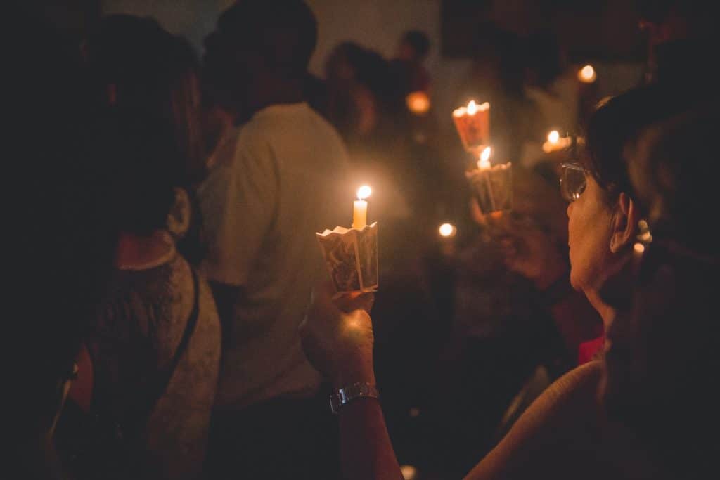 people holding lighted candles during nighttime