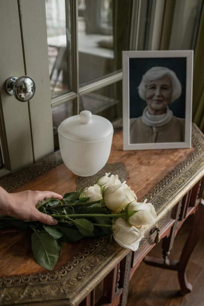 A Picture of an Elderly Woman and White Roses on a Wooden Table